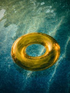 Aerial view of a yellow swim ring in a clear blue pool, perfect for summer concepts.